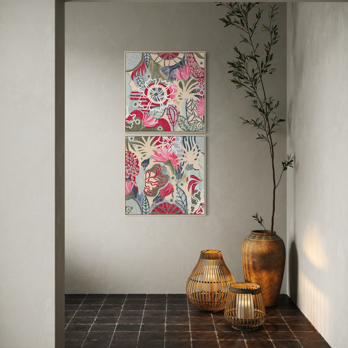 Two vertical framed abstract floral art prints in pink, red, blue, and cream tones hang on a light gray wall above a dark tiled floor, with woven floor lamps and a tall ceramic vase holding a slim plant in the corner.