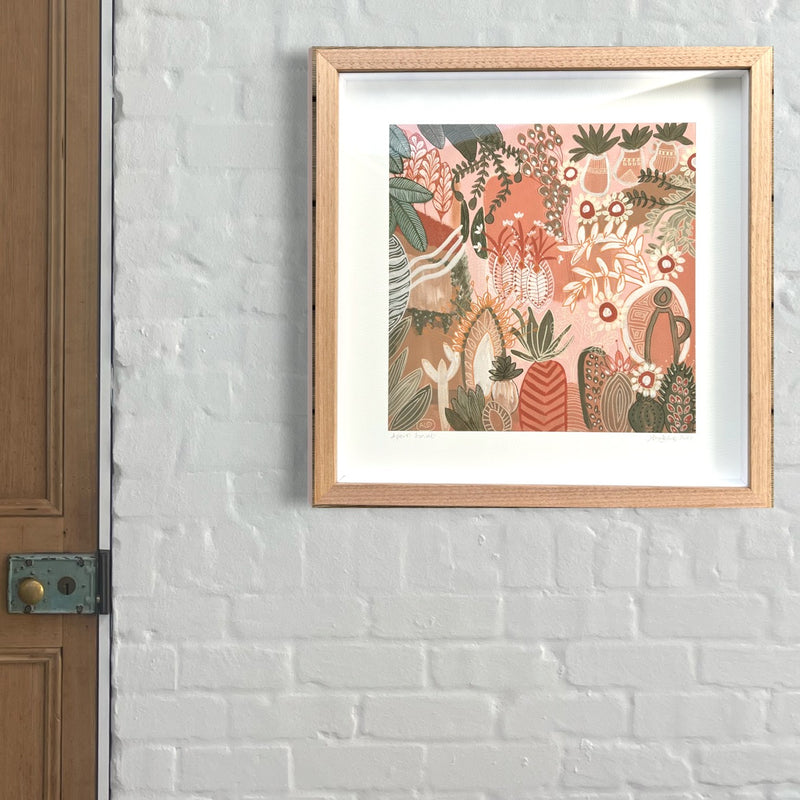 Painting by Anna Lohe framed on wall called Aperol Sunset. Colour palette is peach, terracotta and features botanical imagery