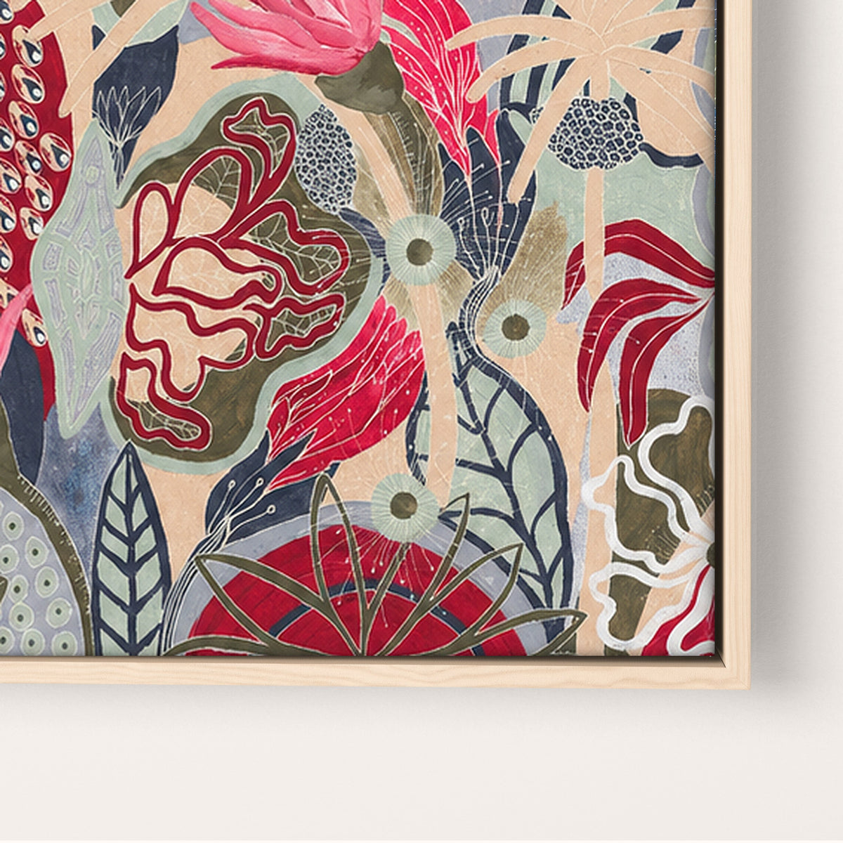 A close-up of framed botanical wall art featuring an abstract floral pattern in red, pink, beige, blue-gray, and olive tones, mounted on a light wall.