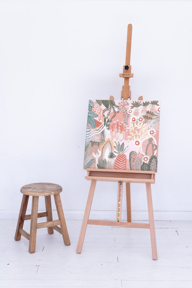 Painting by Anna Lohe on easel called Aperol Sunset. Colour palette is peach, terracotta and features botanical imagery